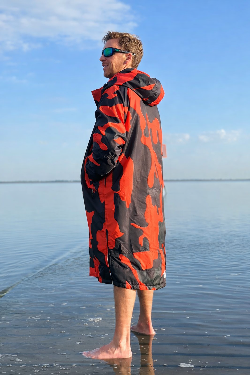 Person wearing an orange and black patterned towel on a beach